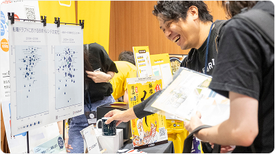 Vue Fes Japan 2024のスポンサーブースを訪れ、展示物を見ながら楽しそうに交流する参加者たち。