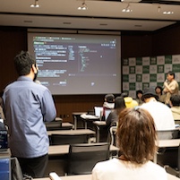 Vue Fes Japan 2024のハンズオンセッションで、右手にマイクを持ち、左手でスクリーンを指差しながら説明をするubugeeei。