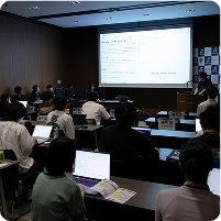 Vue Fes Japan 2024のハンズオンセッション中、スライドを見ながらノートパソコンで作業する参加者たち。講師は前方で説明を行っている。